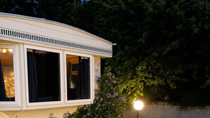Un edificio blanco con un balcón, una jardinera de madera con flores y una farola.