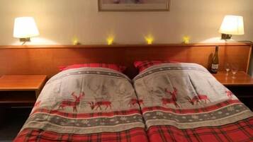 Ein Hotelzimmer mit einem Bett, das mit einer roten Karodecke bezogen ist, zwei Nachttischen mit Lampen und einem Gemälde an der Wand.