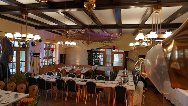 Un comedor con mesas redondas, sillas y adornos colgantes.