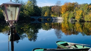 Un lago tranquilo con un farol, un puente de madera y barcos.