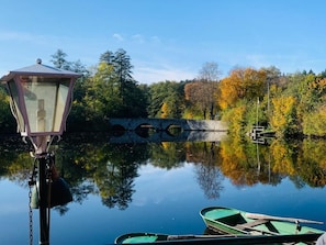 A calm lake with a lamp post, a wooden bridge, and boats.