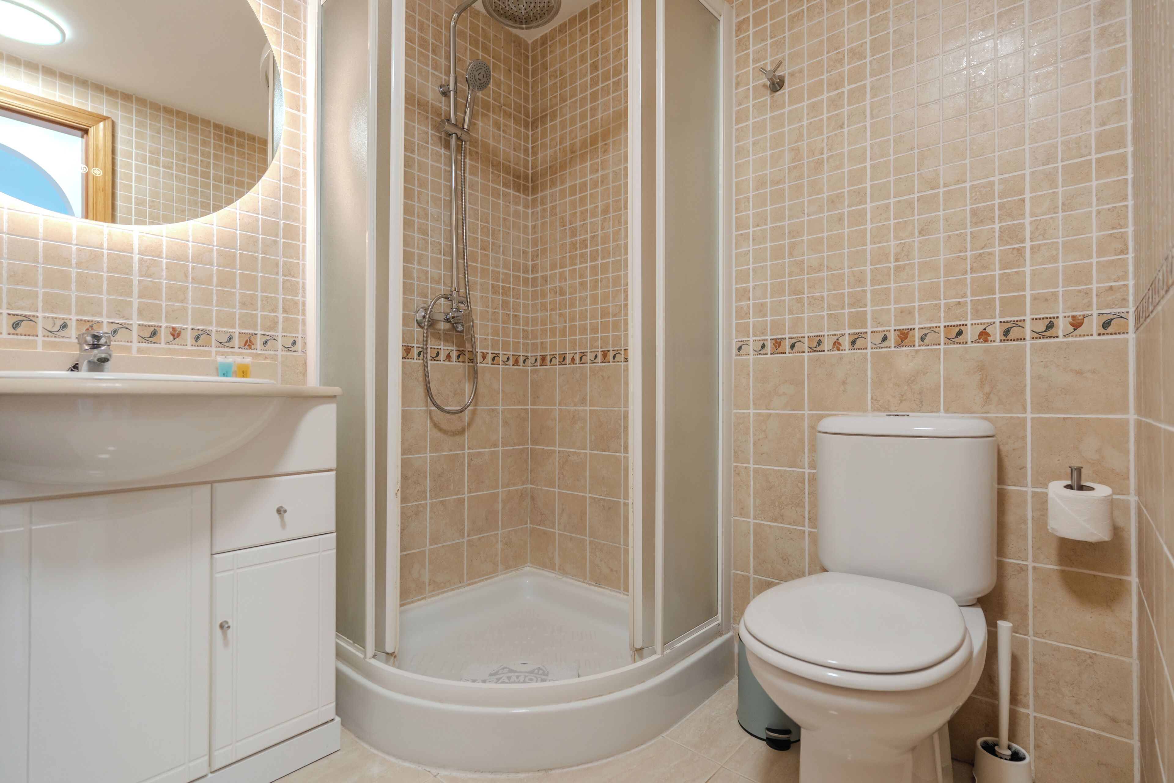 Ein Badezimmer mit Dusche, Toilette, Waschbecken und Schränken.