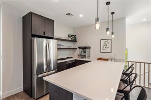 A modern kitchen with a stainless steel refrigerator, a popcorn machine, and pendant lighting. - Villa 4 at Troon North, Luxury Golf Retreat with Pool Table (Scottsdale)