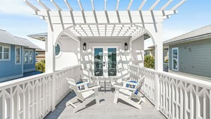 A covered outdoor seating area with white railings and two chairs. - NEW LISTING - Completely remodeled with new pics coming soon. (Seacrest Beach)