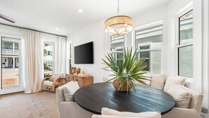 A modern living room with a round table, comfortable seating, a large potted plant, and a flat-screen TV mounted on the wall. - NEW LISTING - Completely remodeled with new pics coming soon. (Seacrest Beach)