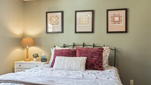 A neatly made bed with floral bedding, a bedside lamp, and three framed artworks on the wall. - Downtown Sisters | Walk to Everything | Sleeps 7 (Sisters)