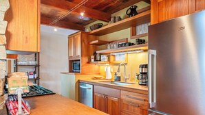 A kitchen with wooden cabinets, a stainless steel refrigerator, a microwave, and a coffee maker. - Downtown Sisters | Walk to Everything | Sleeps 7 (Sisters)