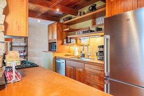 A kitchen with wooden cabinets, a stainless steel refrigerator, a microwave, and a coffee maker.