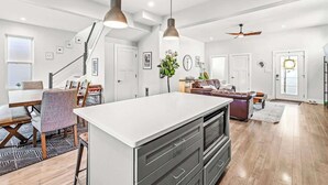 Una cocina moderna con una isla central, iluminación colgante y un ventilador de techo.