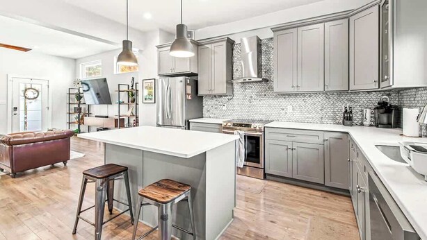 Una cocina moderna con una isla central, electrodomésticos de acero inoxidable y salpicadero blanco.