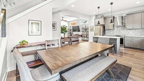 Una cocina moderna con zona de comedor, que incluye una mesa de madera grande y asientos tipo banco.
