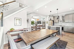 A modern kitchen with a dining area, featuring a large wooden table and bench seating. - Stylish Indy Retreat in a Great Location (Indianapolis)