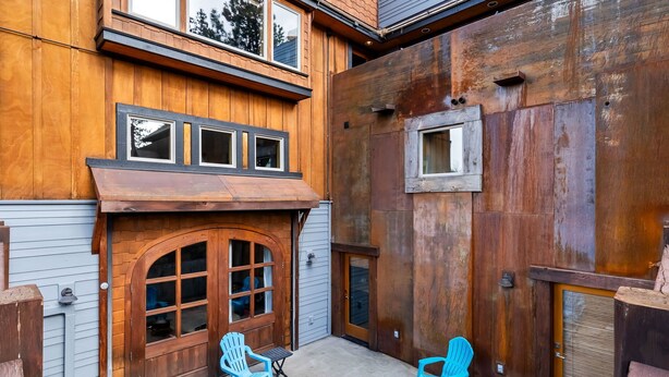 A building with a wooden facade, a double door, and two blue chairs.