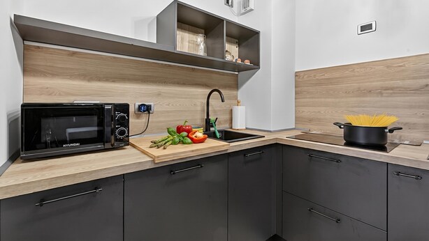 A modern kitchen with a microwave, wooden countertop, and a pot of spaghetti. - L'anemone Near Campo Smith Lifts (Bardonecchia)