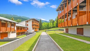 A modern hotel with a central pathway, wooden balconies, and a mountain backdrop. - L'anemone Near Campo Smith Lifts (Bardonecchia)