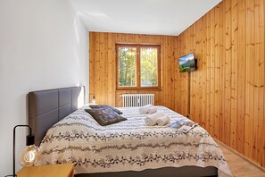 A bedroom with a bed, a TV, a radiator, and a window. - L'anemone Near Campo Smith Lifts (Bardonecchia)