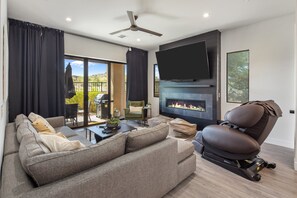 A modern living room with a flat-screen TV, a fireplace, a reclining chair, and a sofa. - Villa 1 at Troon North, Luxury Golf Retreat with Pool Table (Scottsdale)
