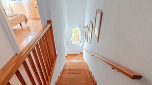 Eine Holztreppe mit Handlauf, die zu einem Zimmer mit Bett und Fenster führt.