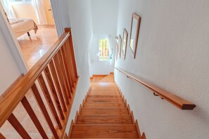 A wooden staircase with a handrail, leading to a room with a bed and a window. - Conde Sunset View (Costa Adeje)