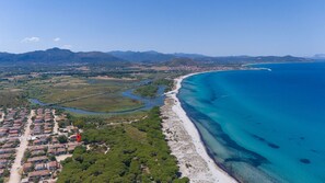 Eine Vogelperspektive einer Küstenlandschaft mit Strand, Wohnhäusern und einem Fluss.