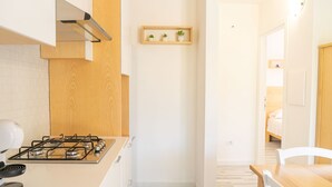 Una cocina moderna con estufa a gas, gabinetes de madera y un pequeño estante con plantas.