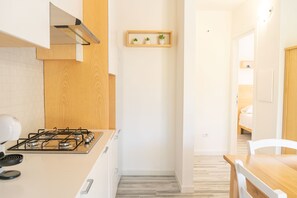 Eine moderne Küche mit Gasherd, Holzschränken und einem kleinen Regal mit Pflanzen.