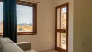 Una habitación con sofá, ventana y puerta que da a un balcón.