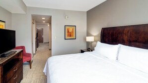 Una camera d'albergo con un letto, una televisione, una scrivania, una sedia, una lampada e un quadro appeso al muro.