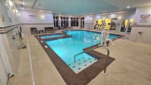 Una grande piscina coperta con diverse corsie, un posto di salvataggio e un cartello che indica assenza di bagnini.