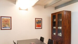 Ein Essbereich mit einem Holztisch, Stühlen, gerahmten Bildern und einer Vitrine mit Glastüren.