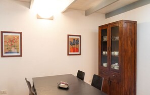 Ein Essbereich mit einem Holztisch, Stühlen, gerahmten Bildern und einer Vitrine mit Glastüren.