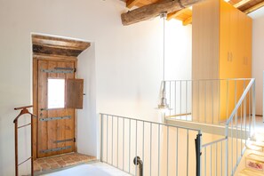 Eine Holztür mit Fenster, einem Metallgeländer und einer Treppe, die zu einer oberen Ebene führt.