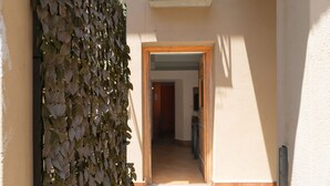 Ein Flur mit einer Holztür am Ende, einem Fliesenboden und einer mit Pflanzen bewachsenen Wand.