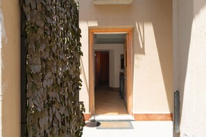 Ein Flur mit einer Holztür am Ende, einem Fliesenboden und einer mit Pflanzen bewachsenen Wand.