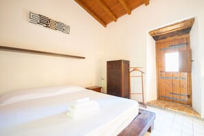 Ein Schlafzimmer mit einem Bett, einem Holzschrank und einer Tür mit Fenster.