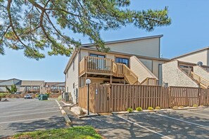 A two-story building with a balcony, a parking lot, and a wooden fence. - Club Ocean Villa II 37 by Seaside Vacations & Sales (Ocean City)