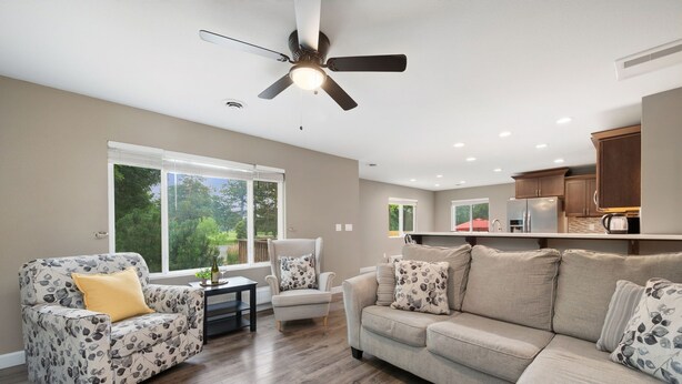 A living room with a sofa, armchair, and a ceiling fan.