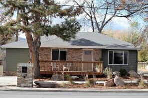 A single-story house with a stone mailbox, a wooden deck, and a small front yard with rocks and plants. - City Park Retreat | Near Golf, Parks & Old Town (Fort Collins)