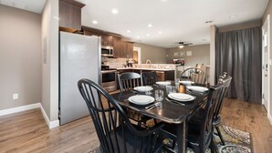 A dining area with a table set for six, kitchen cabinets, a refrigerator, and a microwave.