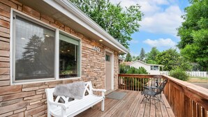 A house with a stone exterior, a deck with a bench and a table, and a number '255' on the wall.