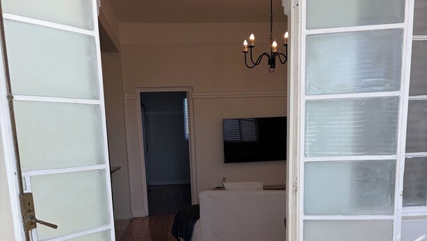 Ein Zimmer mit einem Bett, einem an der Wand befestigten Fernseher und Holzboden.