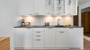Una cocina moderna con armarios blancos, encimera negra, cafetera, fregadero y un frutero.