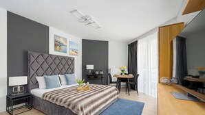 Una habitación de hotel moderna con cama, mesita de noche, escritorio, silla y un espejo grande.