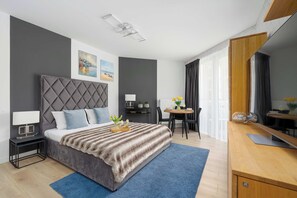 A modern hotel room with a bed, bedside table, desk, chair, and a large mirror. - Cozy Studios Near the Beach | Parking (Pobierowo)