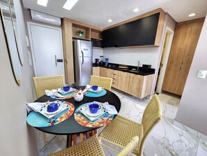 A modern kitchen with wooden cabinets, a stainless steel refrigerator, and a black countertop. - Porto Atlantis 308, just steps from the ocean in Porto de Galinhas (Ipojuca)