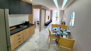 Eine moderne Küche mit Holzausstattung, einer schwarzen Arbeitsplatte und einem Essbereich mit einem runden Tisch und gelben Stühlen.