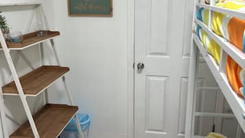 Une chambre avec un lit superposé, des étagères en bois, une porte blanche et une citation encadrée accrochée au mur.