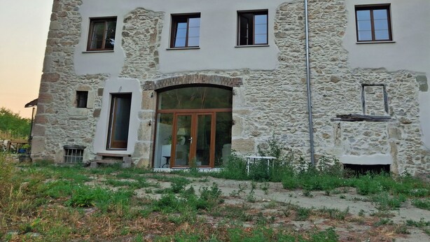 Un immeuble à étages doté d’une façade en pierre, de nombreuses fenêtres et d’une entrée centrale avec des portes en verre.