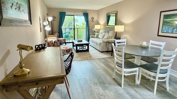 Sala de estar com mesa de jantar, cadeiras, sofá, mesa de centro e varanda com vista.