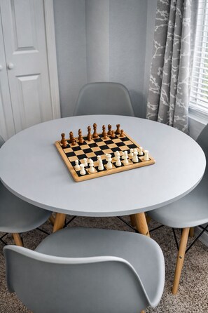 A round table with a chessboard in the center, surrounded by four grey chairs. - Beautiful, cozy & sensory‑friendly home, community pool, playground walking path (Haines City)